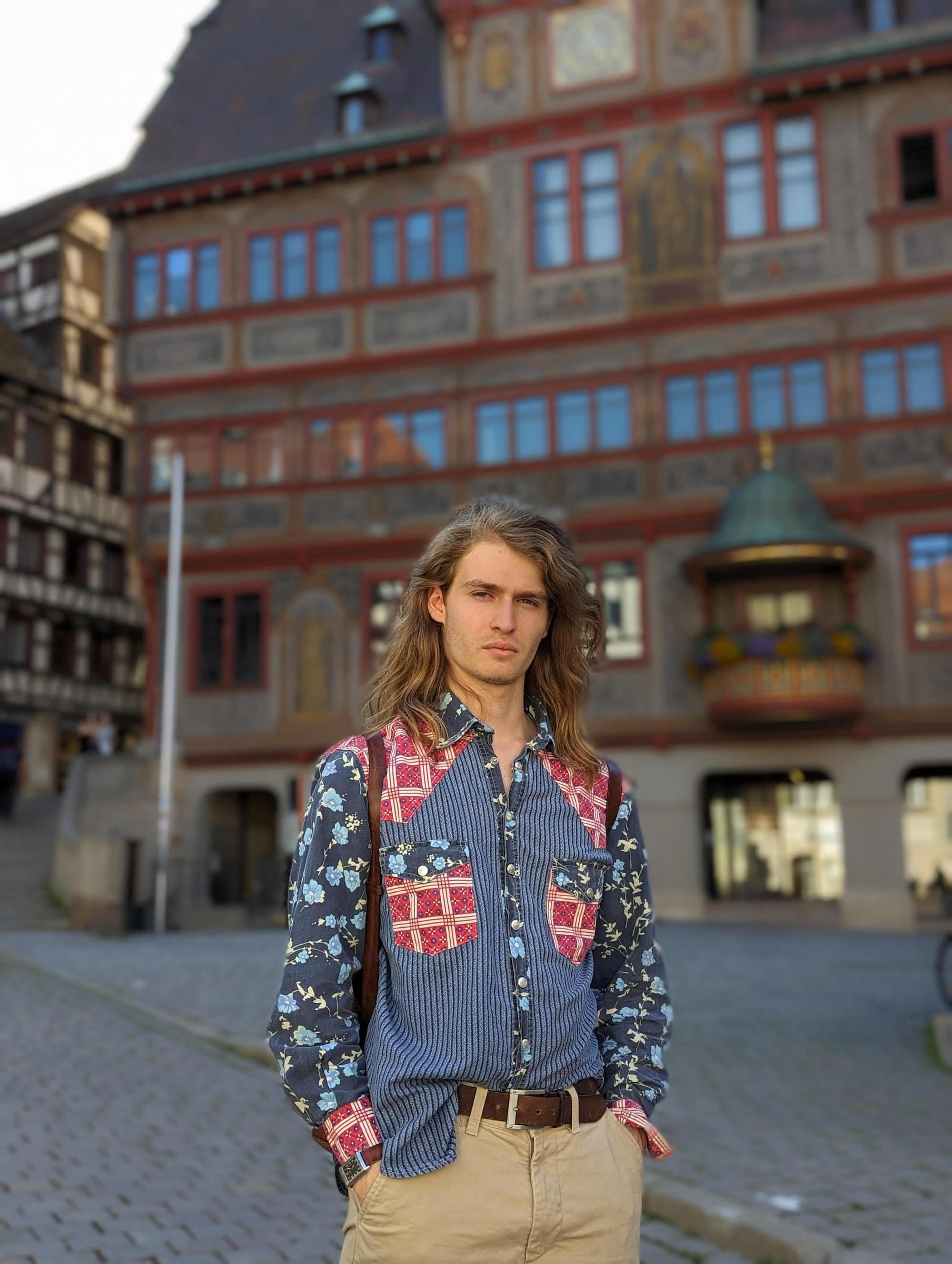 Ein junger Mann trägt steht vor dem Tübinger Rathaus in Tübingen und trägt einen regional gefertigten Gürtel und einen Rucksack von Hepco